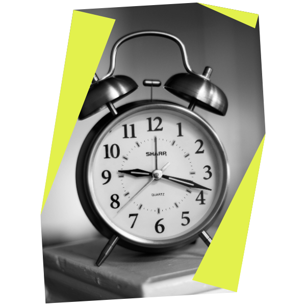 A black and white photo of a vintage twin-bell alarm clock on a table, showing the time as 8:10. The clock face is clear, framed by bright yellow angular borders reminiscent of rdt enterprises' iconic branding style.